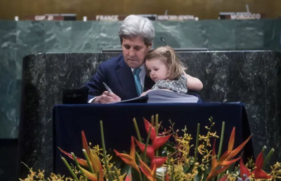 John Kerry signs the Paris Agreement With granddaughter Isabelle on his lap in April 2016 (Pic: UN Photos/Amanda Voisard)